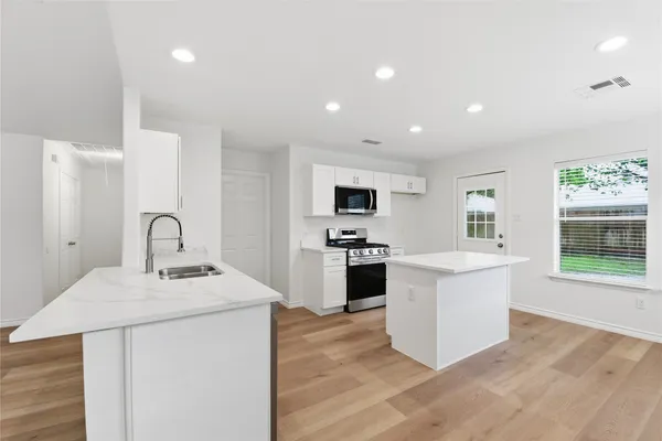 a kitchen with a sink stainless steel appliances and white cabinets
