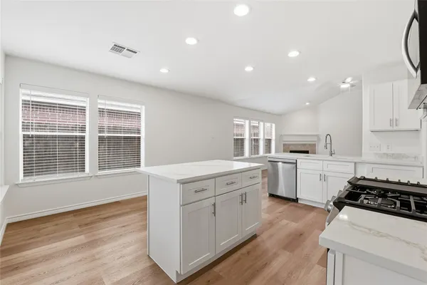 a kitchen with stove a sink dishwasher a refrigerator and white cabinets with wooden floor