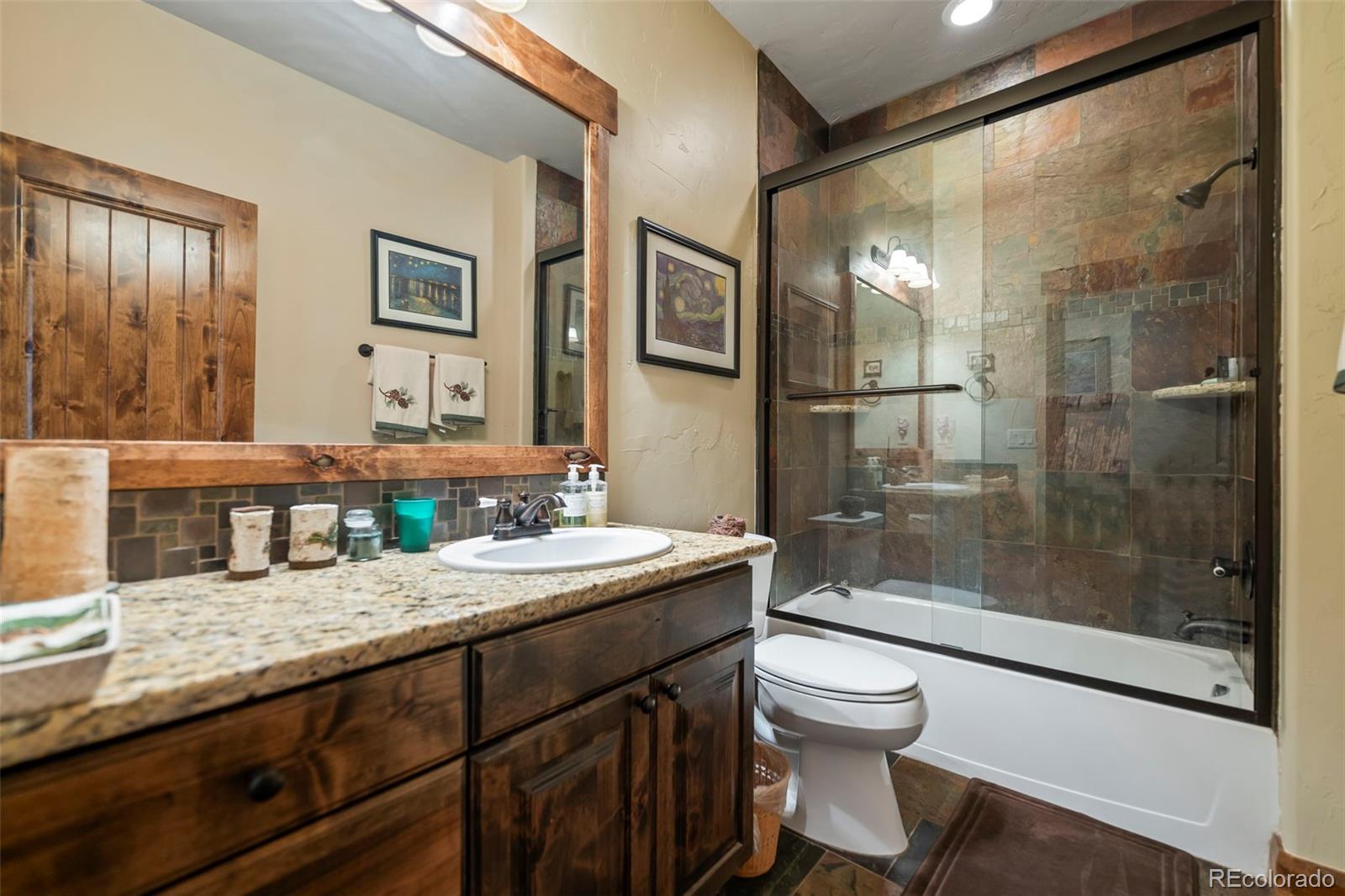 560 Two Cabins Drive Silverthorne, CO 80498 - Photo 22 of 49 a bathroom with a granite countertop sink a toilet a mirror and shower