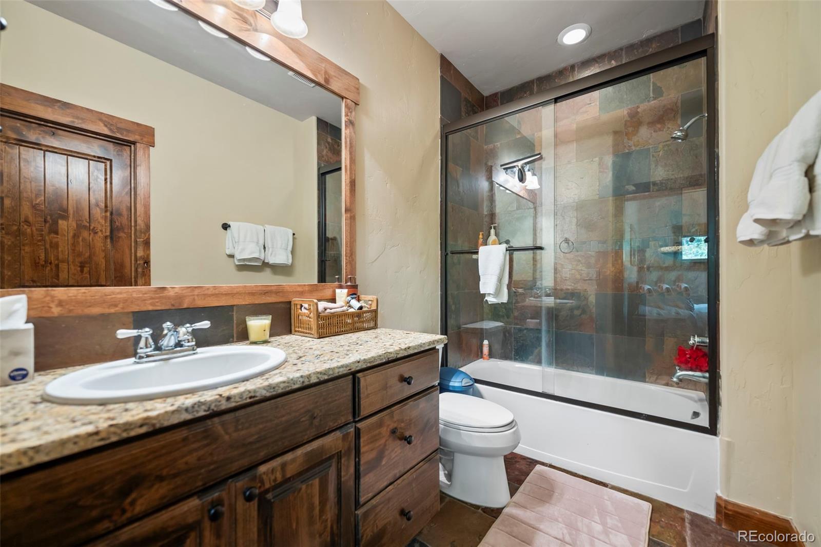 560 Two Cabins Drive Silverthorne, CO 80498 - Photo 26 of 49 a bathroom with a granite countertop sink a toilet a mirror and shower