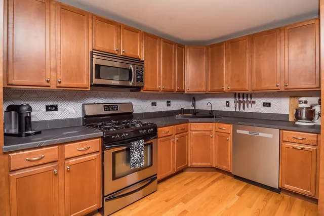 a kitchen with stainless steel appliances granite countertop a stove a sink dishwasher and a microwave oven with cabinets