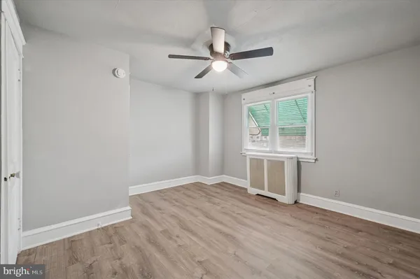 an empty room with wooden floor chandelier fan and windows
