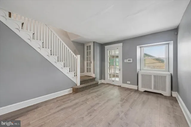 a view of an empty room with wooden floor and stairs