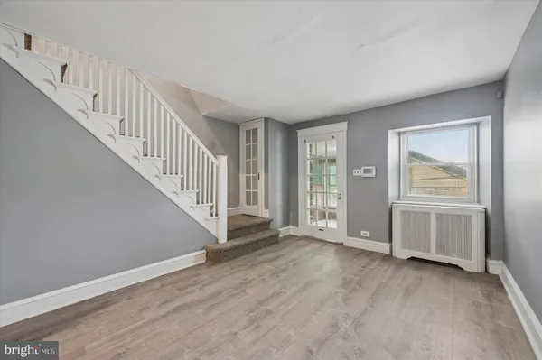 a view of an empty room with wooden floor and stairs