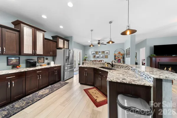 a large kitchen with kitchen island granite countertop wooden cabinets and a wooden floor