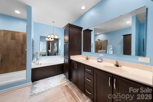 a bathroom with a double vanity sink and mirror with bathtub