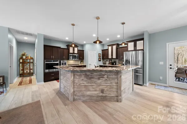 a large kitchen with kitchen island a stove a refrigerator a sink dishwasher and a oven with large cabinets