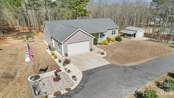 an aerial view of a house with swimming pool and large trees