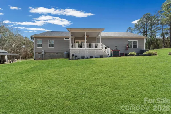 a view of a house with a yard and a large tree