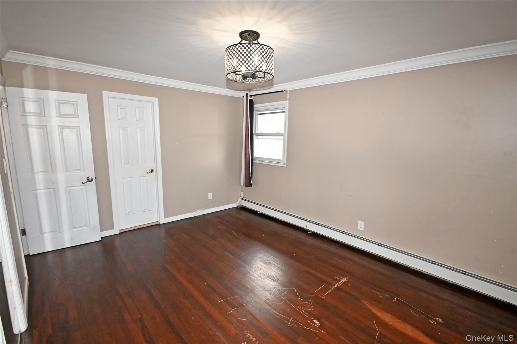 89 Osborne Road West Hempstead, NY 11552 - Photo 12 of 50 Unfurnished bedroom featuring baseboard heating, ornamental molding, and dark wood-type flooring