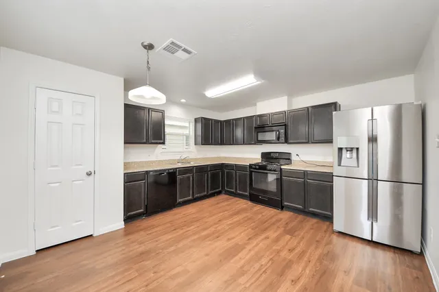 a kitchen with stainless steel appliances granite countertop a refrigerator a sink dishwasher a stove and a refrigerator