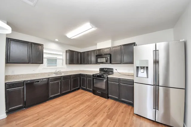 a kitchen with stainless steel appliances granite countertop a refrigerator a sink dishwasher a stove with wooden floors