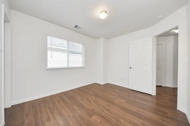 an empty room with wooden floor and windows