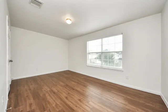 an empty room with wooden floor and windows