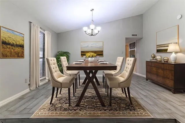 a dining room with wooden floor a chandelier a wooden table and chairs