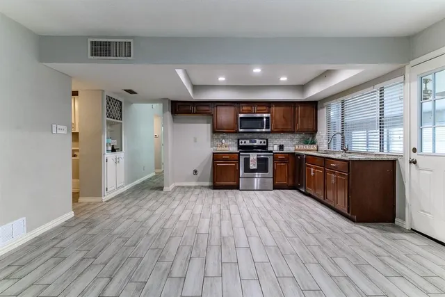 a large kitchen with stainless steel appliances granite countertop a stove cabinets and wooden floor