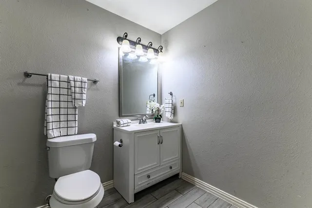 a bathroom with a granite countertop toilet sink and mirror