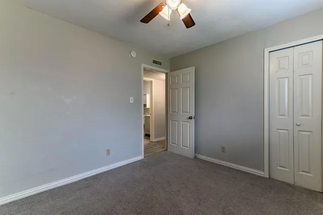 an empty room with a ceiling fan and a window