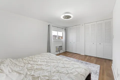 a view of a bedroom with wooden floor and window