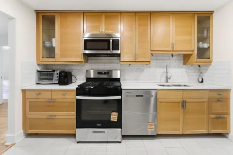 a kitchen with stainless steel appliances granite countertop white cabinets and a stove top oven