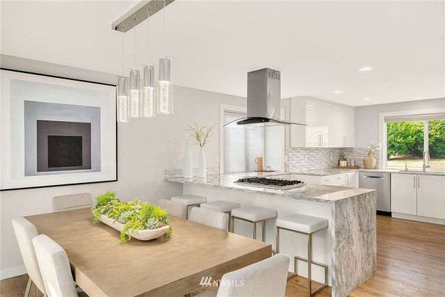 a kitchen with stainless steel appliances kitchen island granite countertop a table and chairs in it