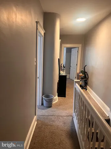 a view of a hallway with wooden floor and a bathroom