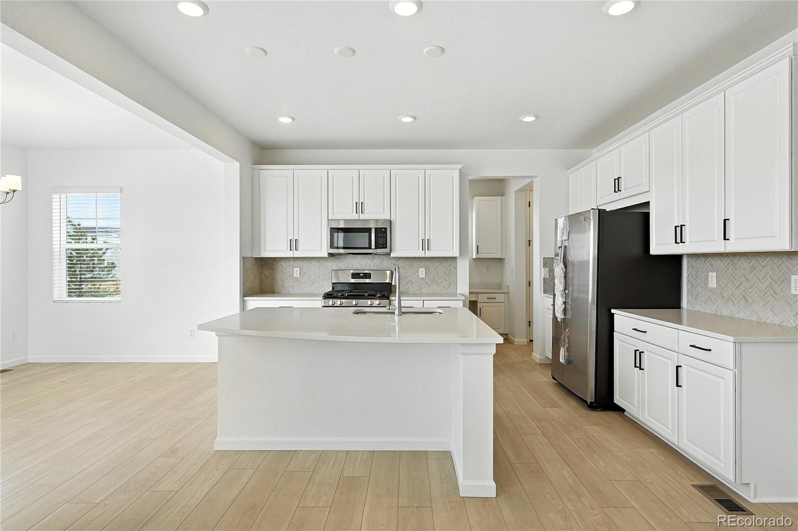 39712 Penn Road Elizabeth, CO 80107 - Photo 3 of 36 a large kitchen with stainless steel appliances granite countertop a stove a sink a refrigerator and white cabinets with wooden floor