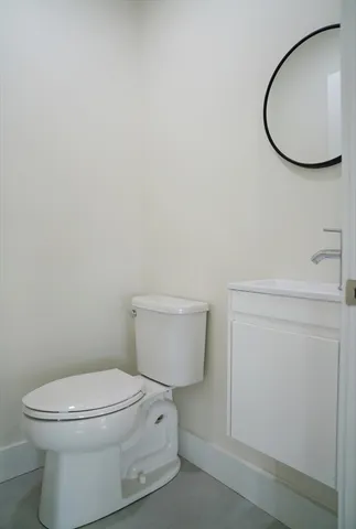 a white toilet sitting next to a white sink and vanity