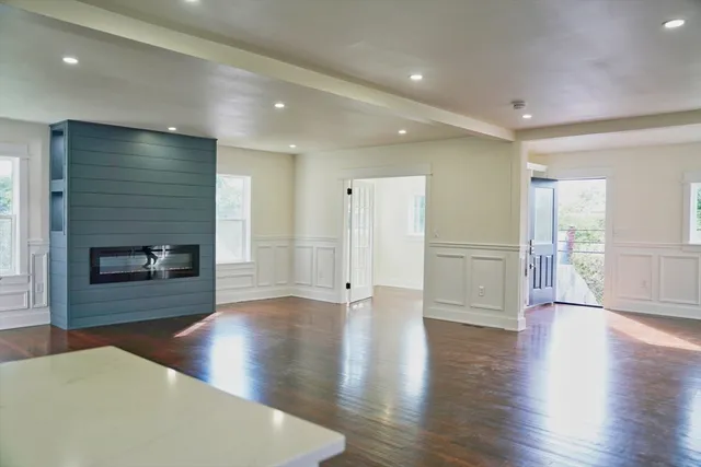 a view of an empty room with wooden floor fireplace and a window