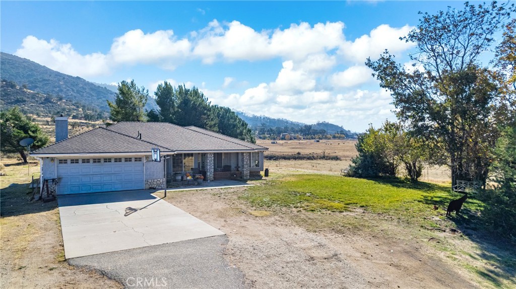 18888 Pellisier Road Tehachapi, CA 93561 - Photo 42 of 43 a view of a white house next to a yard with big trees and plants