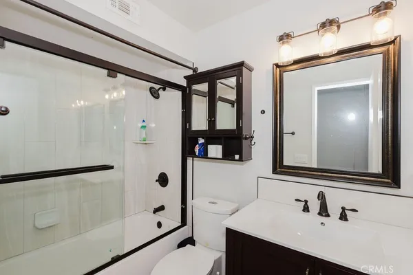 a bathroom with a shower sink vanity mirror and toilet