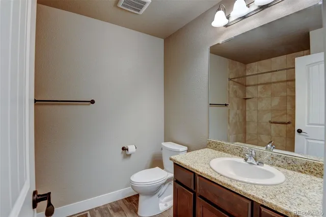 a bathroom with a granite countertop sink toilet and a mirror
