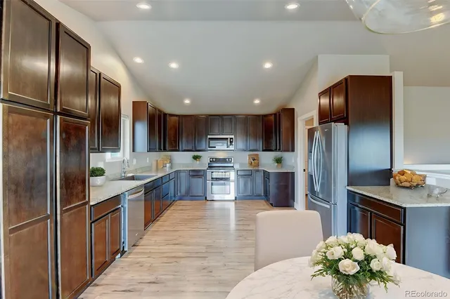 a large kitchen with stainless steel appliances kitchen island granite countertop a refrigerator and a stove top oven