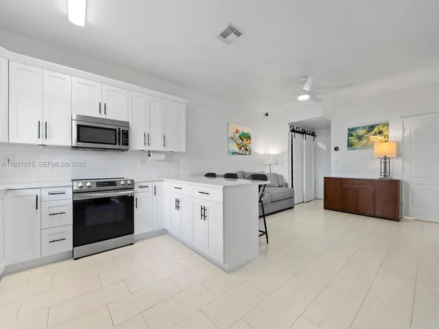 a kitchen with stainless steel appliances a stove a sink a microwave a refrigerator and cabinets