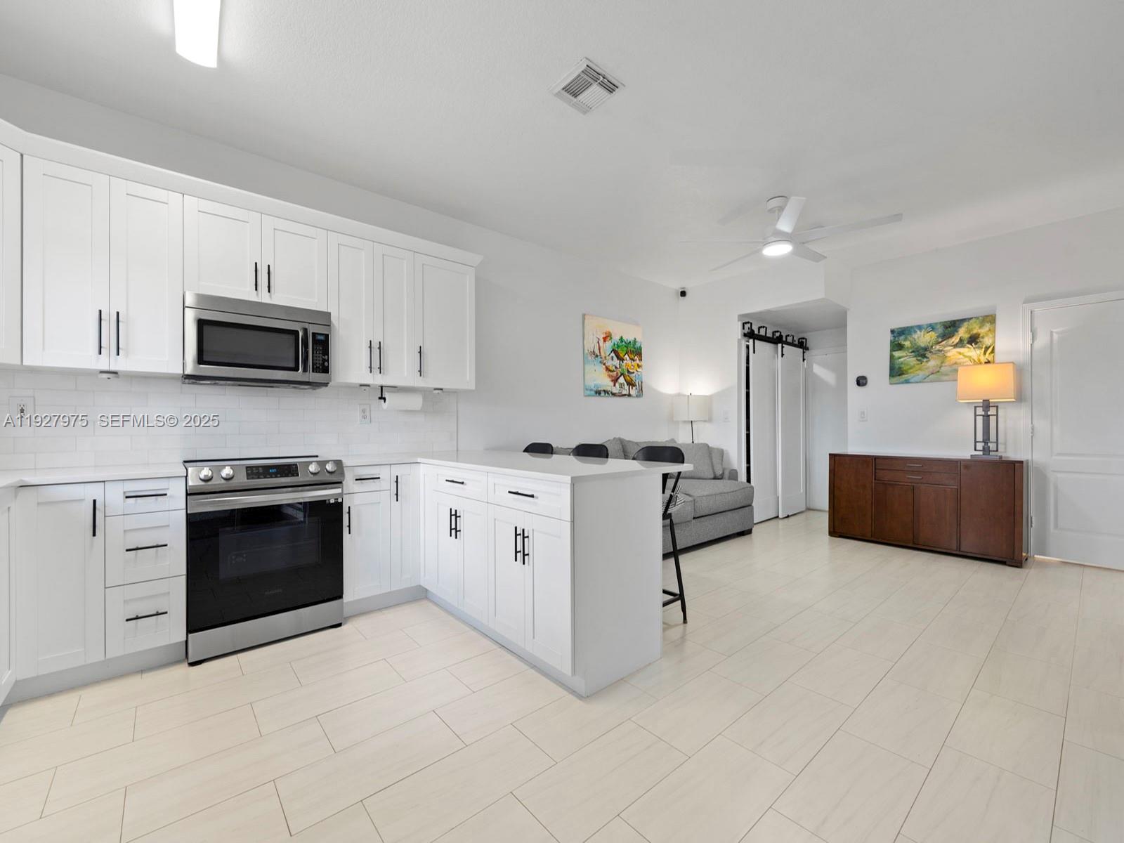 12881 Southwest 49th Court, Unit 12881 Miramar, FL 33027 - Photo 13 of 47 a kitchen with stainless steel appliances a stove a sink a microwave a refrigerator and cabinets