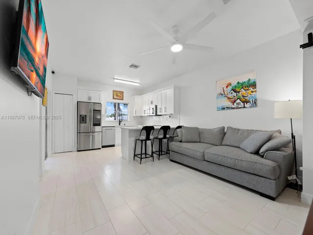 a living room with stainless steel appliances furniture and a kitchen view