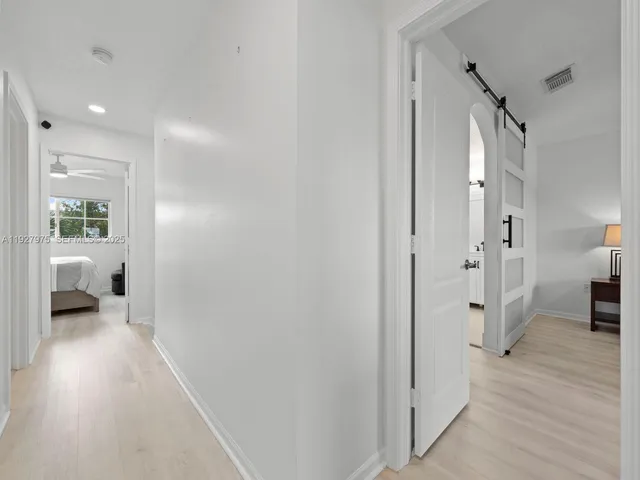 a view of a hallway with wooden floor and a bedroom