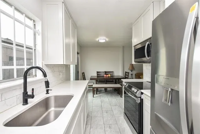 a kitchen with stainless steel appliances granite countertop a sink and a refrigerator