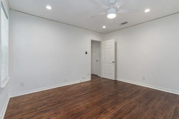 an empty room with wooden floor and windows
