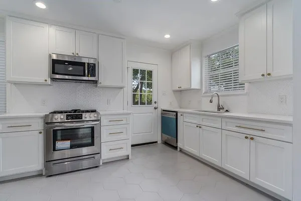 a kitchen with stainless steel appliances white cabinets and a stove top oven