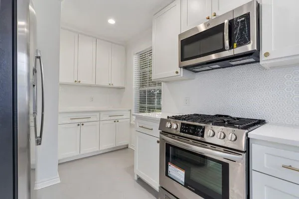 a kitchen with white cabinets and stainless steel appliances