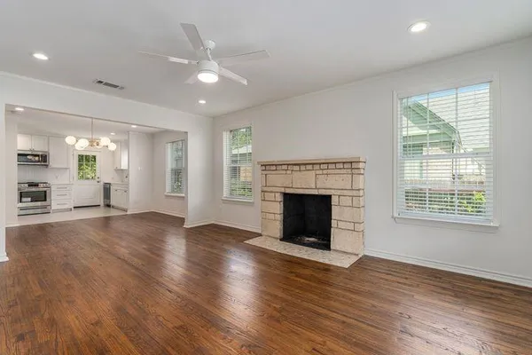 an empty room with wooden floor a fireplace and windows