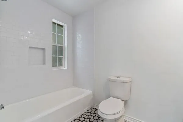 a white toilet sitting next to a tub