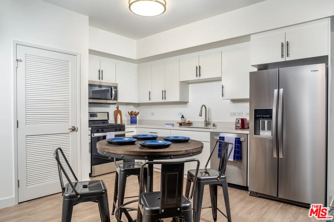 10568 Promenade Gateway, Unit 204 El Monte, CA 91731 - Photo 3 of 34 a kitchen with stainless steel appliances a dining table chairs refrigerator and sink