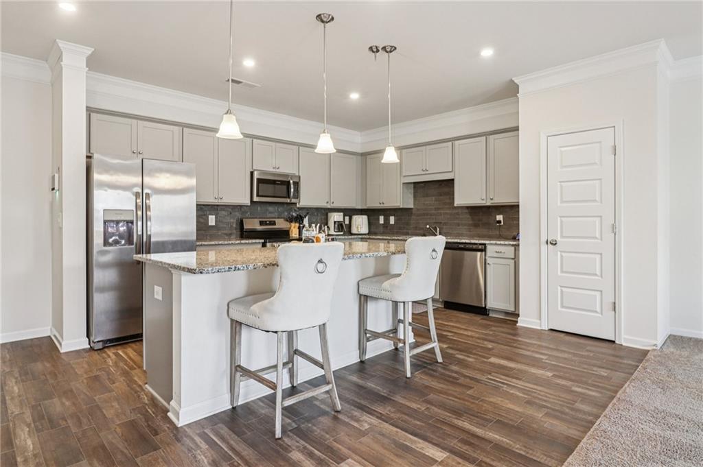 3625 Fairhaven Drive Powder Springs, GA 30127 - Photo 5 of 20 a kitchen with stainless steel appliances kitchen island granite countertop a stove a sink a refrigerator and white cabinets with wooden floor