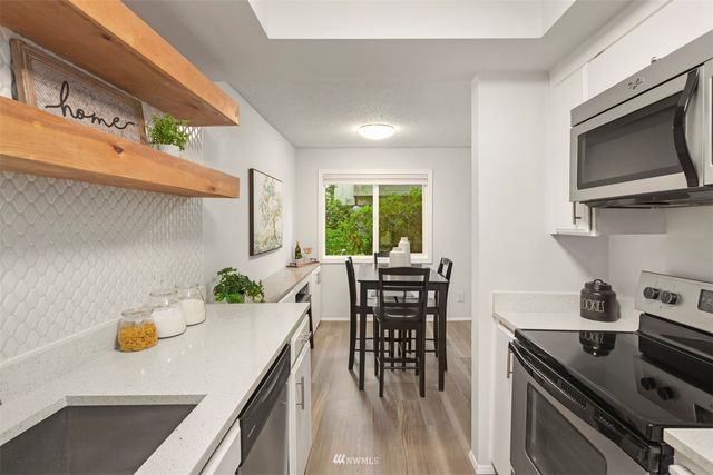 a kitchen with stainless steel appliances a dining table chairs and a wooden floor