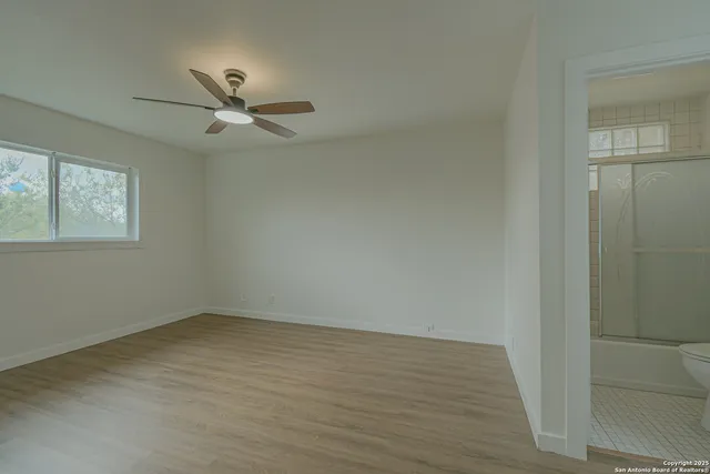 an empty room with a window and ceiling fan