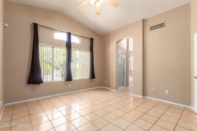 a view of an empty room with window and chandelier fan