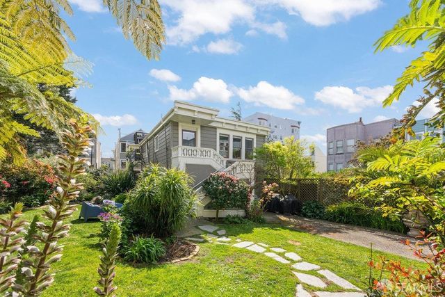 a view of a big yard with plants and large trees