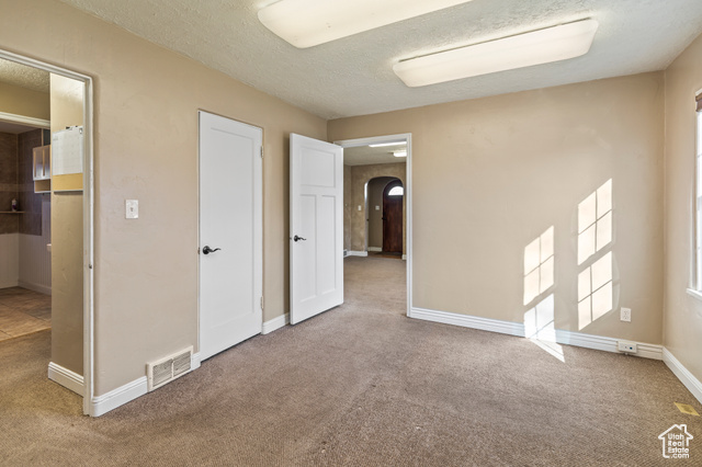 465 North Main Street Richfield, UT 84701 - Photo 12 of 43 Unfurnished bedroom featuring carpet, baseboards, visible vents, arched walkways, and a textured ceiling